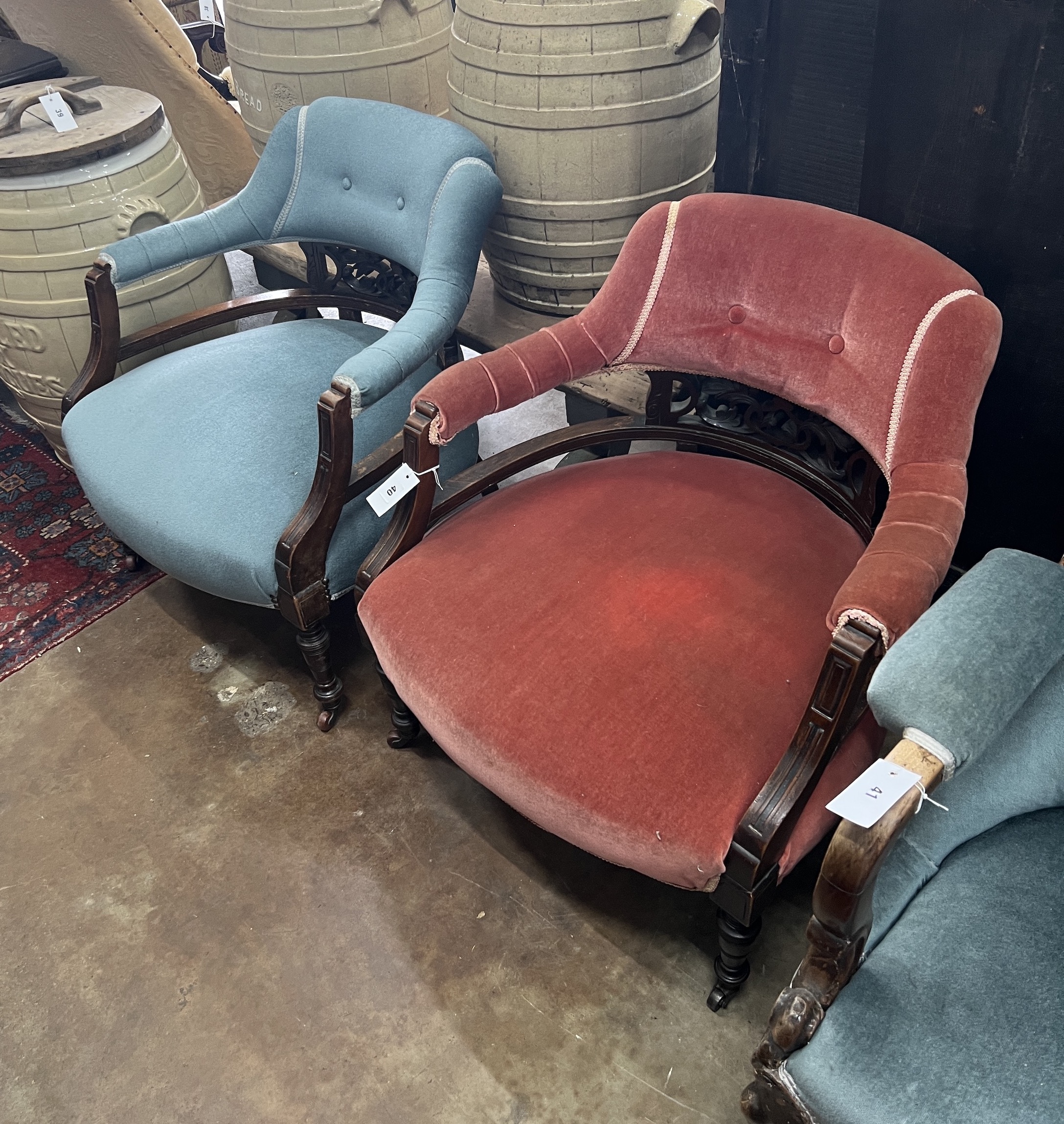 A pair of late Victorian tub shaped open armchairs, upholstered, one in red, the other in blue, width 68cm, depth 58cm, height 72cm